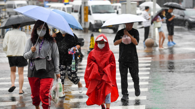 在北京市朝陽區(qū)行人冒雨行走在路上