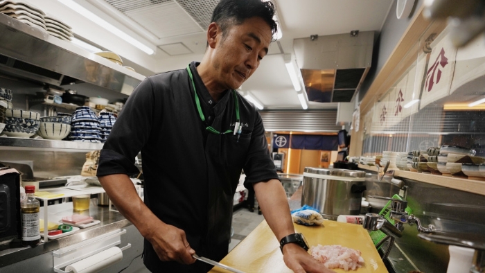 磐城市魚店餐館老板邊切比目魚邊受訪。 美聯(lián)社