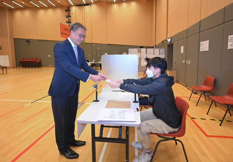 選舉管理委員會(huì)主席陸啟康法官（左）今日（十二月五日）視察位于北角社區(qū)會(huì)堂的模擬投票站，并示范2023年區(qū)議會(huì)一般選舉的正確投票程序。 圖示陸啟康法官示范使用電子選民登記冊(cè)系統(tǒng)領(lǐng)取選票。