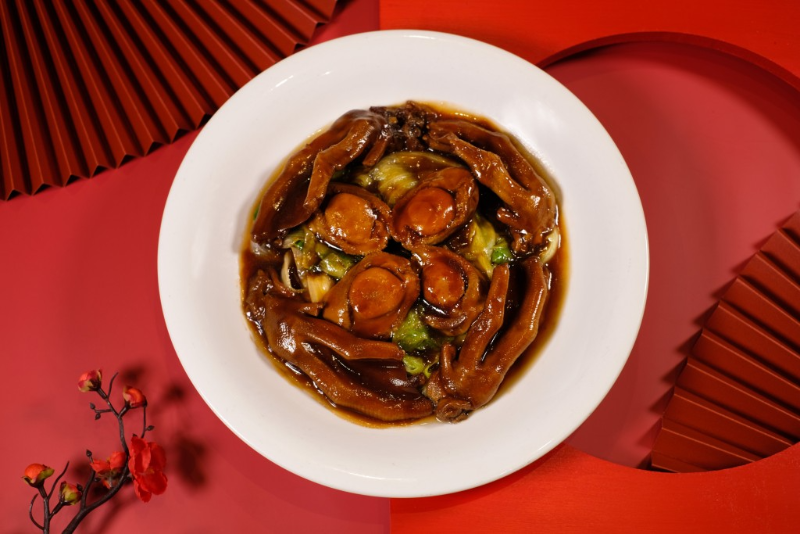 如中菜廳賀年菜——原只6頭鮑魚扣鵝掌（聚寶套餐），鮑魚是賀年菜經(jīng)典食材，葉師傅將其燜至入味配鵝掌上桌，展現(xiàn)傳統(tǒng)風味。