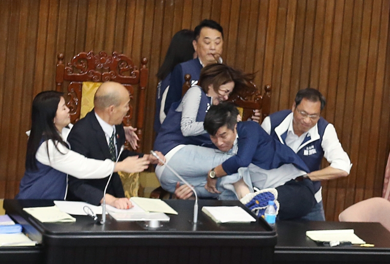 “立法院”17日院會(huì)表決大戰(zhàn)一觸即發(fā)，民進(jìn)黨“立委”鐘佳濱（右二）翻上桌沖向主席臺(tái)，擋在院長(zhǎng)韓國(guó)瑜（左二）前的國(guó)民黨“立委”陳菁徽（中右）前被鐘一把抱住，2人雙雙跌落桌下。 （姚志平攝）