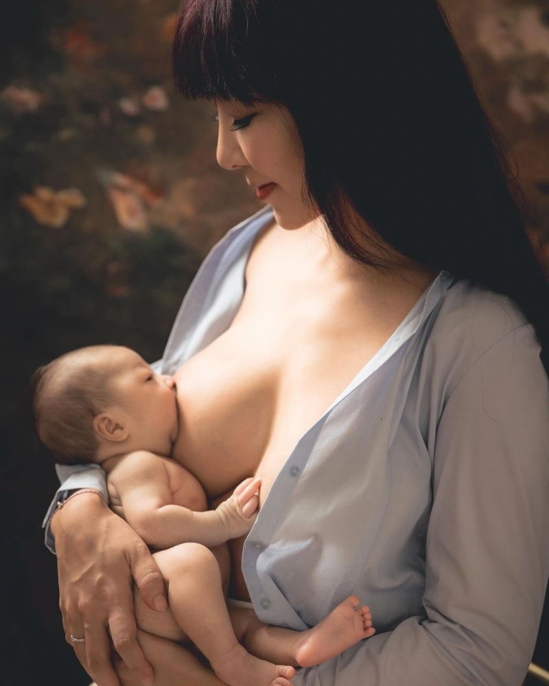 李宓穿上一件淺藍色襯衫，不過就將扣子解開露出35F傲人上圍，并將剛出生的雙胞胎女兒放在大腿上喂母乳及遮住重點部位。