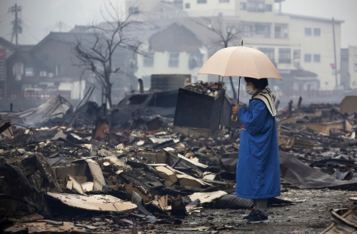 2024年1月1日，日本石川縣能登半島發(fā)生規(guī)模7.6強震，引發(fā)海嘯和大規(guī)?；馂?。 一名婦女站在被大火燒毀的輪島市早市前。 （美聯(lián)社）